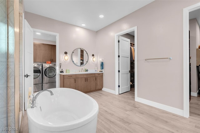 bathroom featuring vanity, independent washer and dryer, hardwood / wood-style flooring, and a washtub