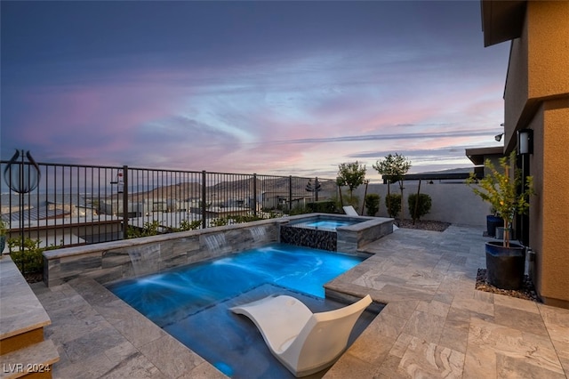 pool at dusk with an in ground hot tub, a patio area, and pool water feature