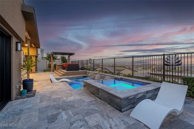 pool at dusk with an in ground hot tub and a patio