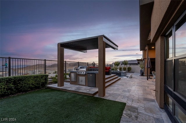 yard at dusk featuring a patio area and an outdoor kitchen