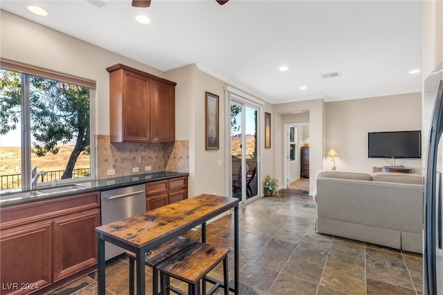 kitchen with sink, dark stone counters, stainless steel dishwasher, and tasteful backsplash