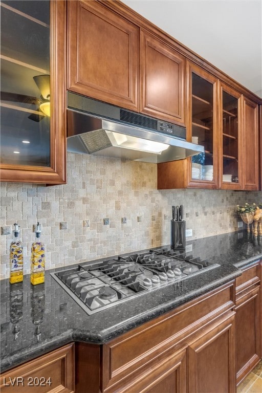 kitchen with dark stone counters, gas stovetop, and tasteful backsplash