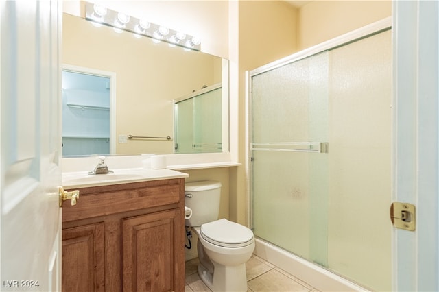 bathroom with vanity, a shower with shower door, toilet, and tile patterned flooring