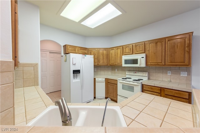 kitchen with tile countertops, sink, white appliances, and tasteful backsplash