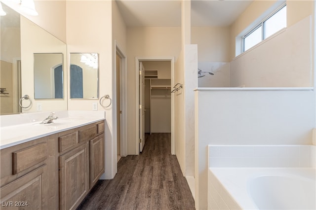 bathroom featuring vanity, tiled bath, and hardwood / wood-style floors