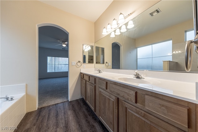 bathroom featuring tiled tub, plenty of natural light, hardwood / wood-style floors, and vanity