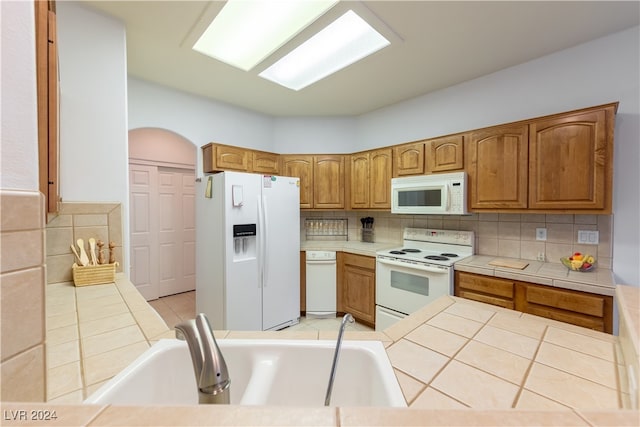 kitchen featuring white appliances, sink, tile countertops, and backsplash