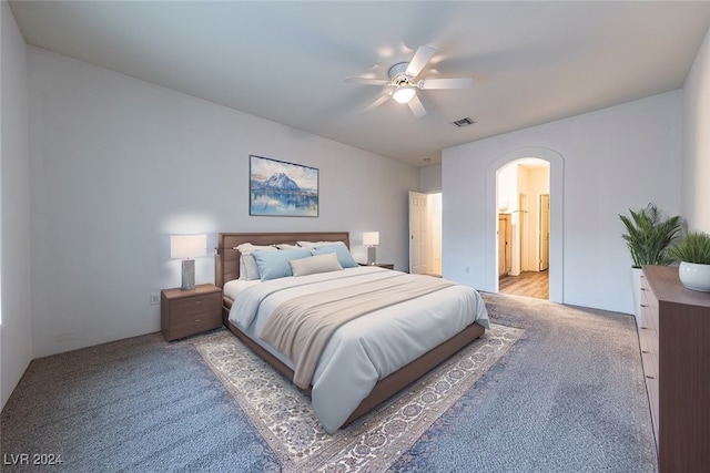 bedroom featuring light carpet, ensuite bath, and ceiling fan