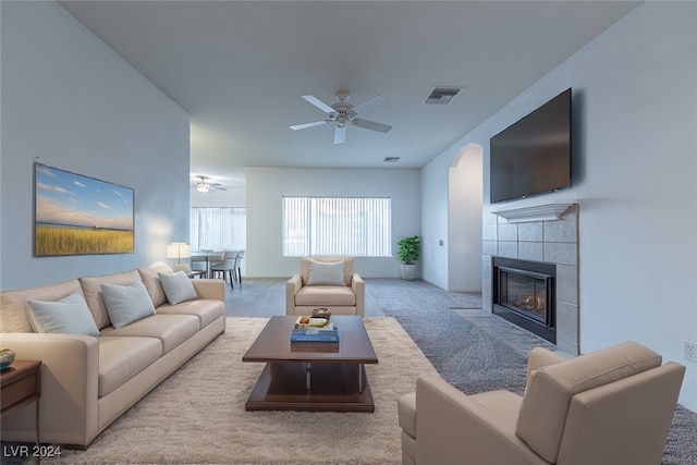 carpeted living room featuring ceiling fan and a tile fireplace