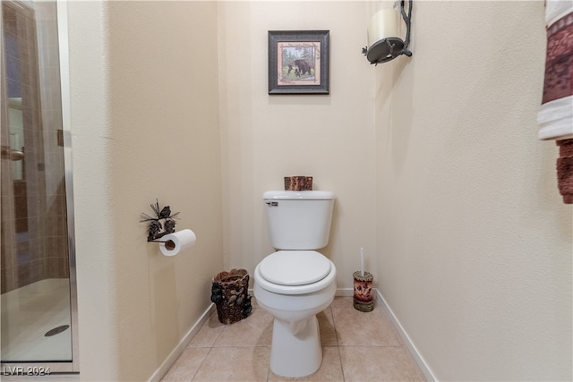 bathroom with toilet, a shower with shower door, and tile patterned floors