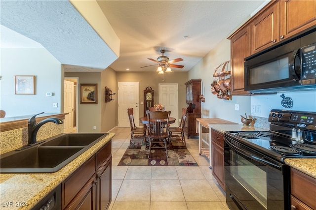 kitchen with sink, black appliances, light tile patterned flooring, light stone counters, and ceiling fan