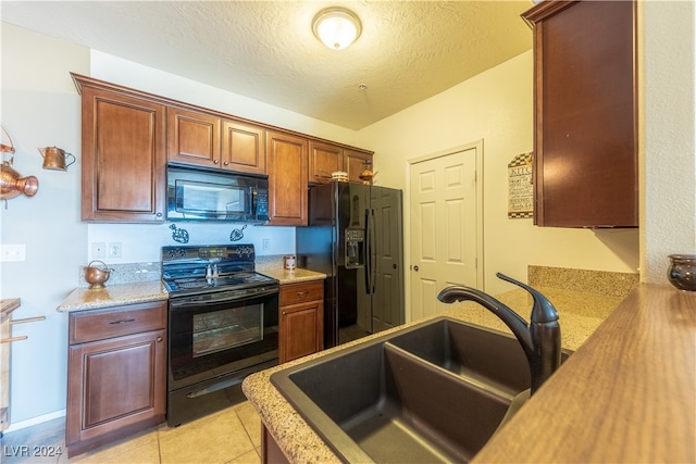 kitchen featuring sink, light tile patterned floors, black appliances, and a textured ceiling