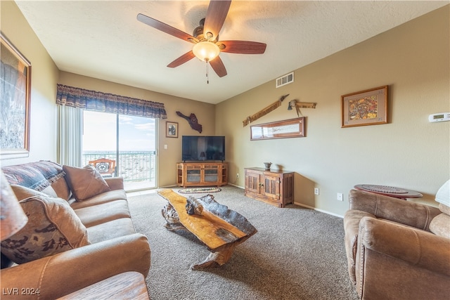 carpeted living room featuring ceiling fan and a textured ceiling