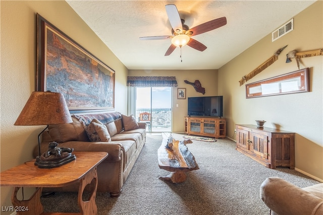 carpeted living room featuring ceiling fan and a textured ceiling