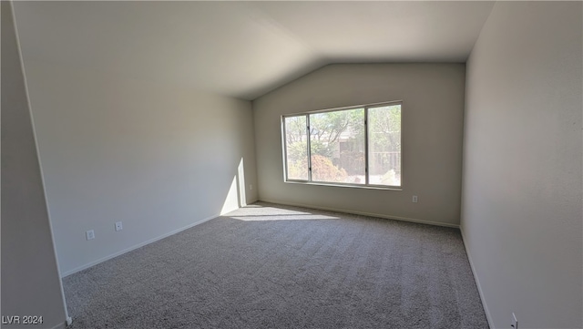 spare room featuring lofted ceiling and light colored carpet