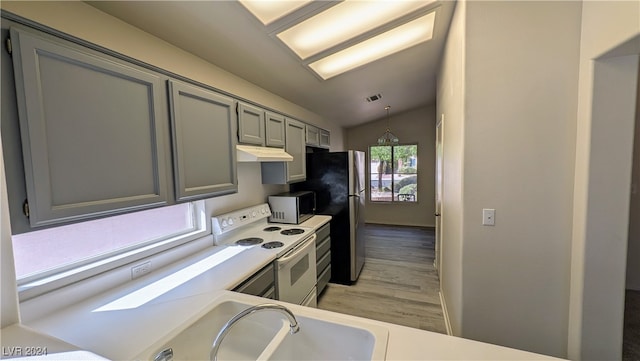 kitchen featuring light hardwood / wood-style floors, vaulted ceiling, hanging light fixtures, gray cabinetry, and appliances with stainless steel finishes