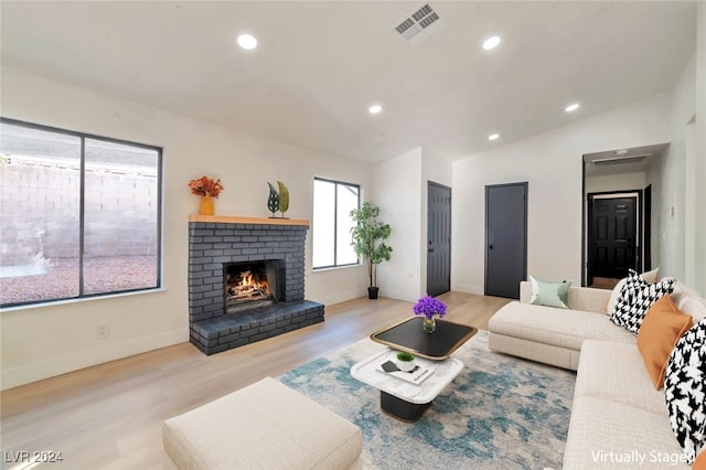 living room featuring a fireplace, light wood-type flooring, and lofted ceiling