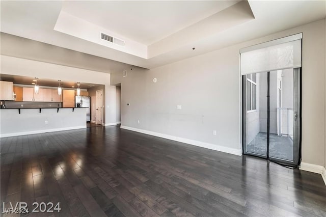 unfurnished living room with a tray ceiling and dark hardwood / wood-style floors