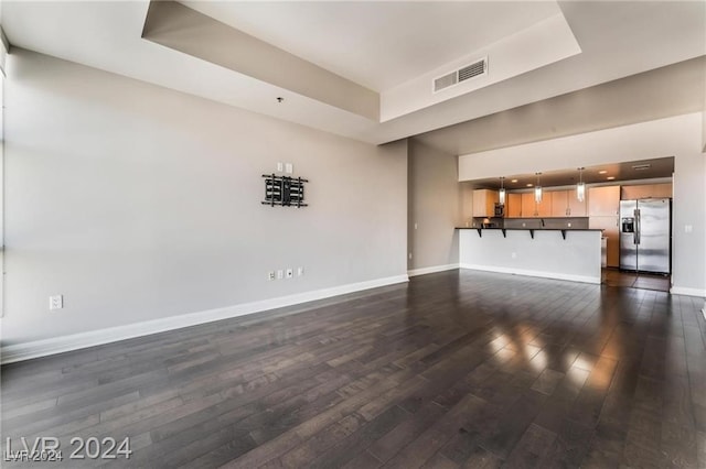 unfurnished living room with a tray ceiling and dark hardwood / wood-style floors