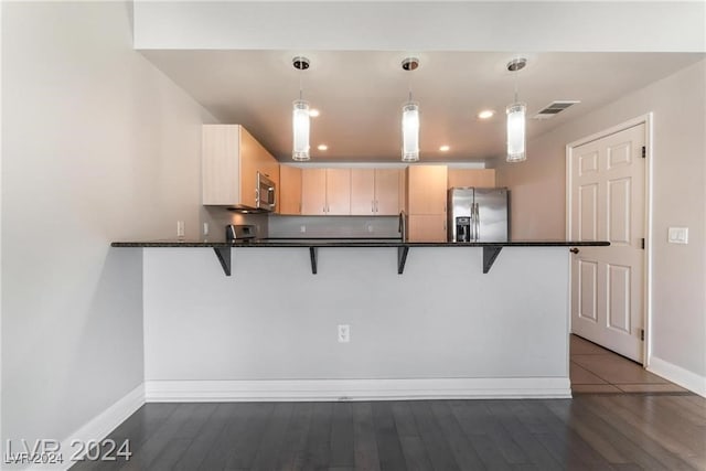 kitchen with kitchen peninsula, dark wood-type flooring, stainless steel appliances, and decorative light fixtures