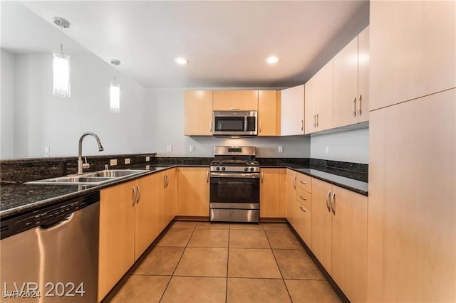 kitchen with light brown cabinets, stainless steel appliances, and decorative light fixtures