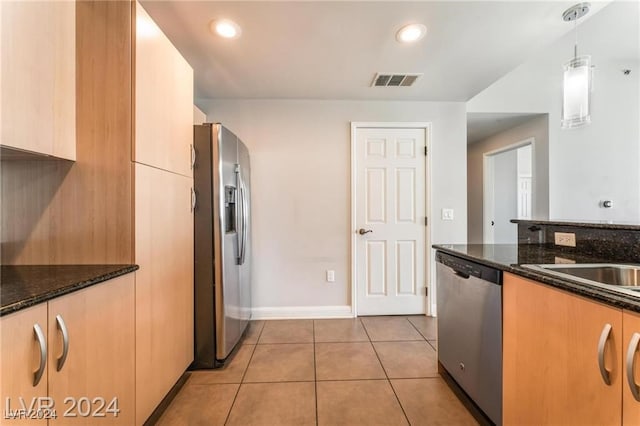 kitchen with pendant lighting, stainless steel appliances, light tile patterned floors, and dark stone counters