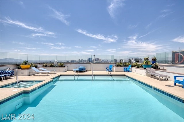 view of swimming pool featuring a hot tub and a patio area