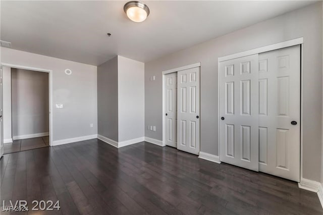 unfurnished bedroom featuring dark hardwood / wood-style flooring and multiple closets