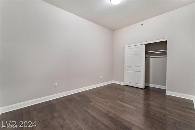 unfurnished bedroom with dark wood-type flooring and a closet