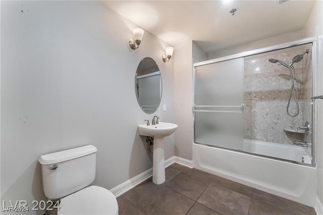 full bathroom with tile patterned flooring, toilet, sink, and bath / shower combo with glass door