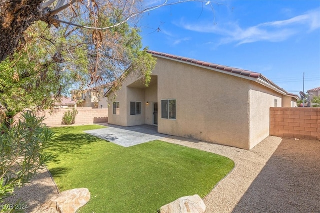 back of property with a lawn and a patio