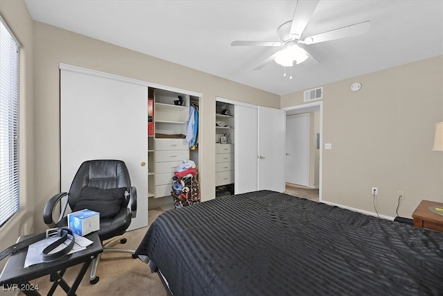 carpeted bedroom with multiple windows, two closets, and ceiling fan