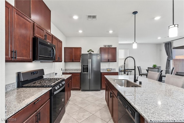 kitchen featuring pendant lighting, light tile patterned floors, sink, a center island with sink, and black appliances