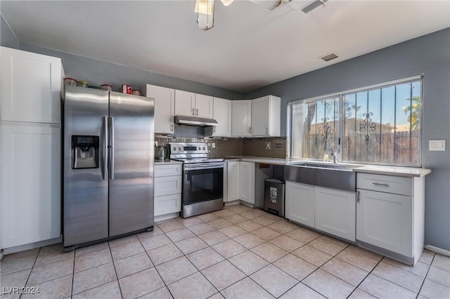 kitchen with tasteful backsplash, sink, white cabinets, appliances with stainless steel finishes, and light tile patterned floors