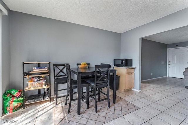 dining space with a textured ceiling and light tile patterned floors