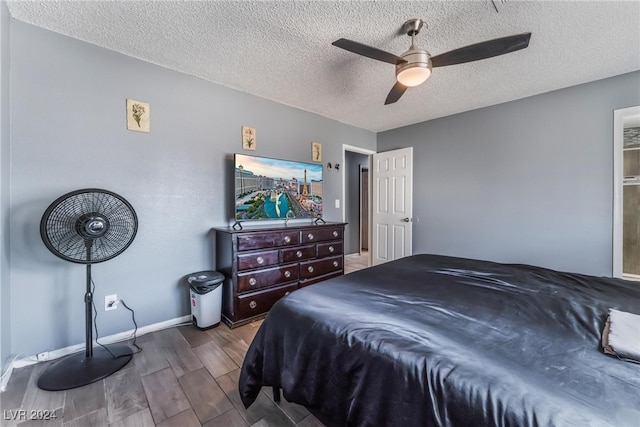 bedroom with ceiling fan, a textured ceiling, and dark hardwood / wood-style flooring