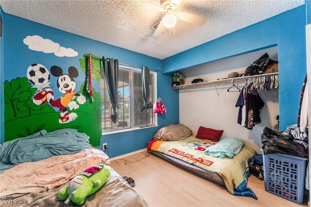 bedroom featuring ceiling fan, a textured ceiling, a closet, and hardwood / wood-style floors