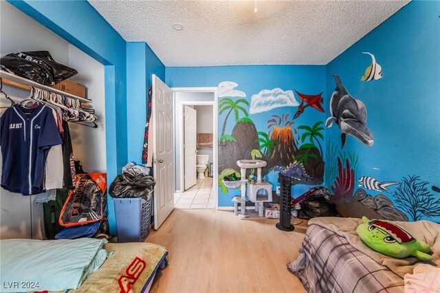 bedroom with light hardwood / wood-style flooring, a textured ceiling, and ensuite bathroom