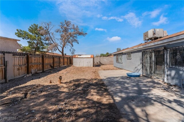 view of yard featuring central AC unit, a storage shed, and a patio