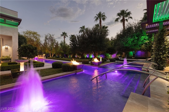 pool at dusk featuring pool water feature