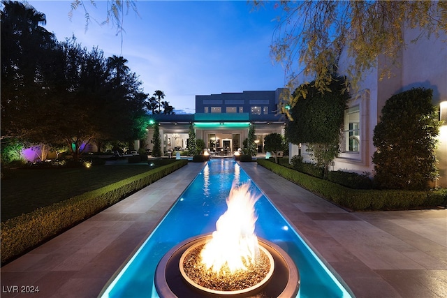 pool at dusk featuring a fire pit