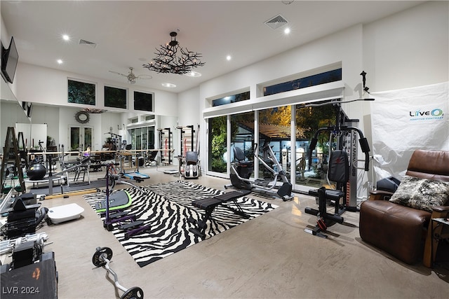 exercise room with ceiling fan and a high ceiling