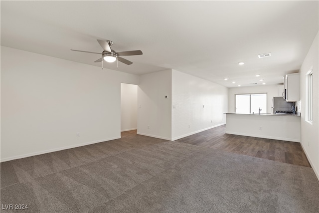 unfurnished living room with ceiling fan and dark wood-type flooring