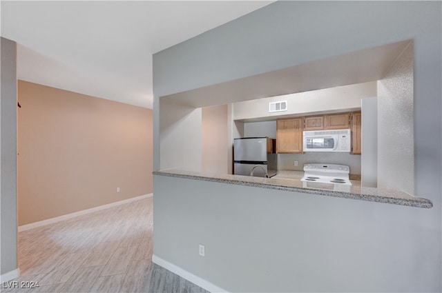 kitchen with light hardwood / wood-style flooring, white appliances, kitchen peninsula, and light stone countertops