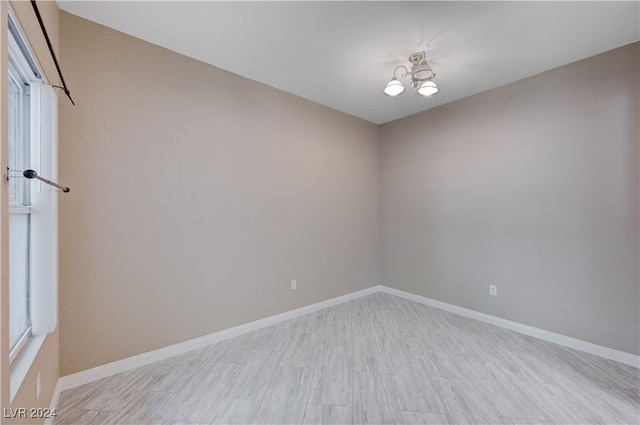 spare room with light wood-type flooring and a chandelier