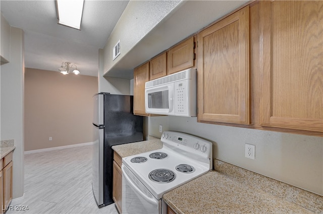 kitchen with white appliances, light brown cabinetry, and a chandelier