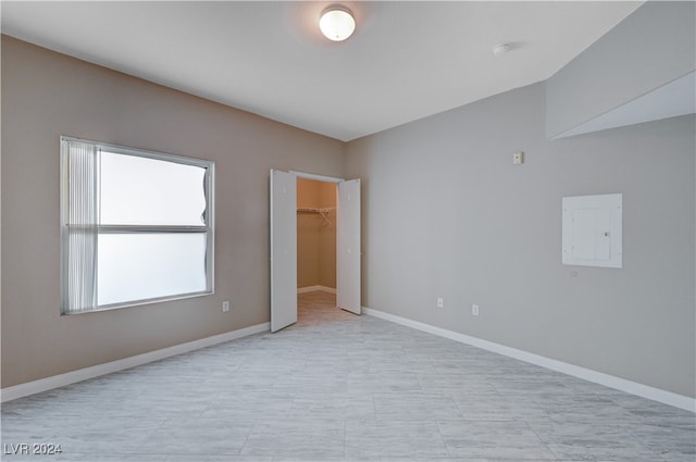 unfurnished bedroom featuring electric panel, a closet, and a walk in closet