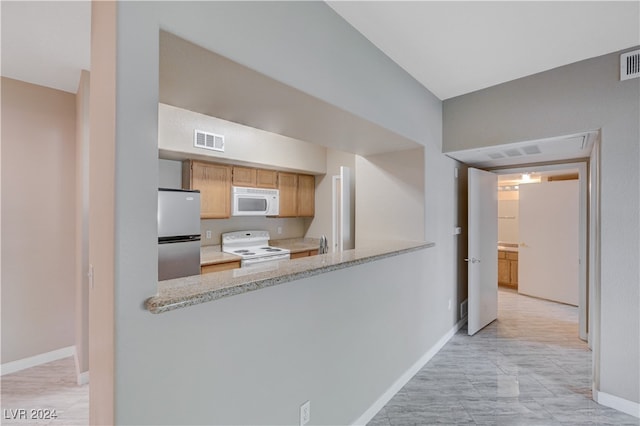 kitchen featuring light stone countertops, white appliances, and kitchen peninsula