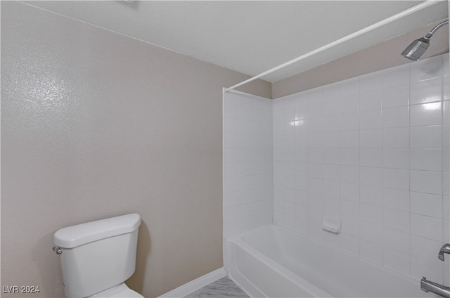 bathroom with tiled shower / bath combo and toilet