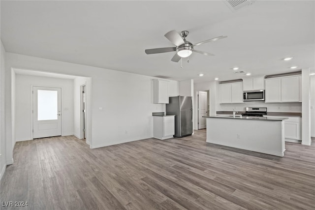 kitchen with an island with sink, stainless steel appliances, white cabinetry, and light hardwood / wood-style floors